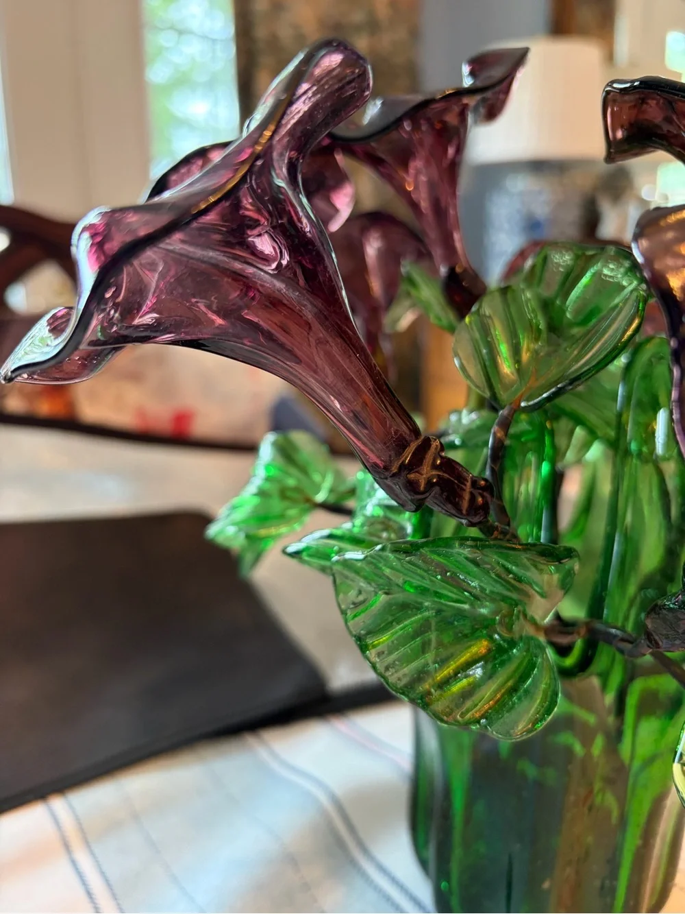 Vintage green swing glass vase with purple lily trumpet flowers.